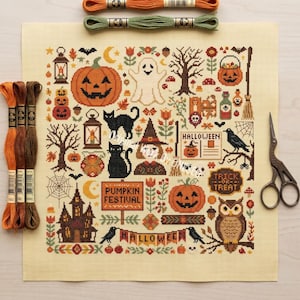 May include: A square piece of cream-colored Aida fabric featuring a cross-stitch pattern with Halloween motifs including pumpkins, a ghost, black cats, an owl, a haunted house, and text reading Pumpkin Festival, Halloween, and Trick or Treat.