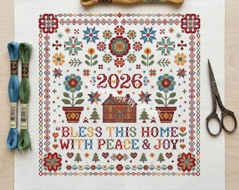 Puede incluir: Una tela de punto de cruz blanca con un patrón colorido que incluye el año 2026, una casa, flores y el texto BLESS THIS HOME WITH PEACE & JOY, acompañada de cuatro madejas de hilo de bordar en rojo, amarillo, azul y verde, y tijeras de metal.