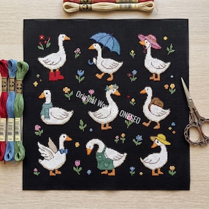 May include: Cross-stitch pattern featuring nine white geese, each adorned with unique accessories like hats, scarves, and an umbrella, set against a black background with floral accents. The text "Original World ONESEO" is visible.