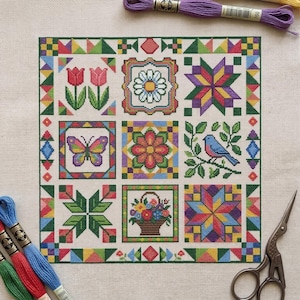 Könnte beinhalten: Ein farbenfrohes Kreuzstichmuster mit neun Quadraten, die verschiedene Designs wie Blumen, einen Schmetterling und Sterne zeigen. Das Muster zeigt einen Blumenkorb, einen blauen Vogel und geometrische Muster. Stickgarn und Schere sind sichtbar.