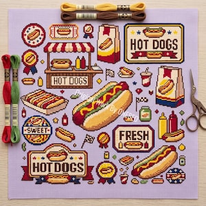 May include: A cross-stitch pattern on light purple fabric featuring various hot dog illustrations, including food stands, condiment bottles, and signs with the text HOT DOGS and FRESH. Includes two skeins of embroidery floss and metal scissors.