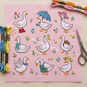May include: Cross-stitch pattern featuring nine geese, each adorned with unique accessories like boots, hats, and a scarf. The geese are set against a pink background with floral accents. Embroidery floss and scissors are visible.
