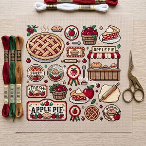 May include: A square piece of beige Aida fabric featuring a cross-stitch pattern of apple pies, baskets of apples, rolling pins, and a bakery stand. The design includes text reading APPLE PIE, SWEET, FRESH, and BAKERY. Three embroidery floss skeins and scissors are present.