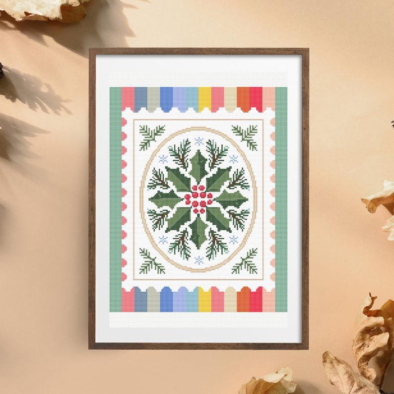 Puede incluir: Arte de punto de cruz enmarcado con un dise&ntilde;o ovalado central de hojas verdes de acebo y bayas rojas. El dise&ntilde;o est&aacute; rodeado por un borde de rayas coloridas y un borde verde, creando un tema festivo de vacaciones.