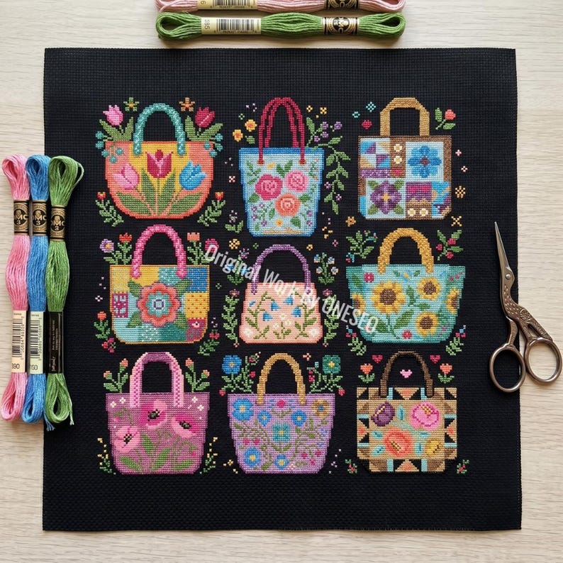 Puede incluir: Un cuadrado de tela negra con un patr&oacute;n de punto de cruz de nueve bolsos coloridos decorados con varios dise&ntilde;os florales y geom&eacute;tricos. Tres madejas de hilo de bordar en rosa, azul y verde, y unas tijeras de metal est&aacute;n colocadas cerca.