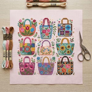Puede incluir: Un patr&oacute;n de punto de cruz sobre tela rosa claro que muestra nueve bolsos con dise&ntilde;os florales y geom&eacute;tricos. Tres madejas de hilo de bordar en azul claro, rosa y marr&oacute;n est&aacute;n a la izquierda, y unas tijeras plateadas a la derecha.