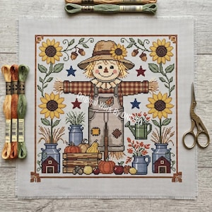 May include: A cross-stitch design featuring a scarecrow with a straw hat and overalls, surrounded by sunflowers, pumpkins, and fall foliage. The design includes the text "Original Work By CNSusan". The color palette includes shades of brown, yellow, orange, and blue.