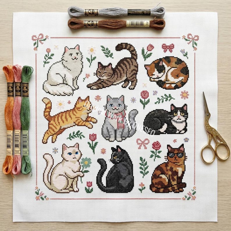 May include: A cross-stitch pattern featuring nine different cat designs in various poses and colors, surrounded by floral and bow motifs. Embroidery floss and scissors are also visible, suggesting a crafting project.