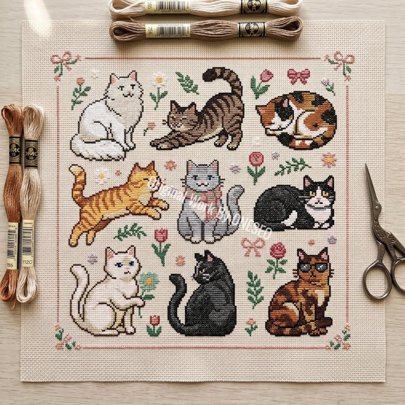 May include: A cross-stitch pattern featuring nine different cat designs in various colors and poses, surrounded by floral and bow motifs. Embroidery floss and scissors are visible, suggesting a crafting theme.