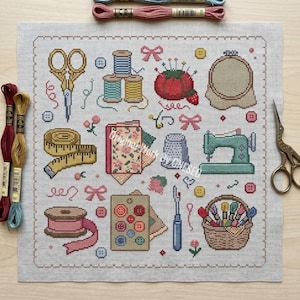 May include: A cross-stitch pattern on light fabric featuring sewing motifs including gold scissors, spools of thread, a red pincushion, an embroidery hoop, a yellow measuring tape, a floral fabric swatch, a thimble, a sewing machine, buttons, a seam ripper, and a basket of thread.
