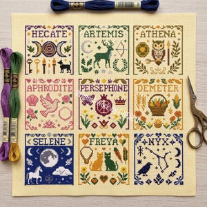 May include: A cross-stitch pattern on cream fabric featuring nine squares with names and symbols of goddesses: Hecate, Artemis, Athena, Aphrodite, Persephone, Demeter, Selene, Freya, and Nyx. Includes two embroidery floss skeins and metal scissors.