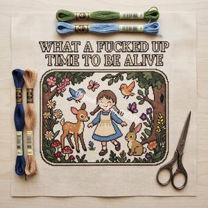 May include: A cross stitch pattern on beige fabric featuring a girl, a deer, and a rabbit in a forest with the text WHAT A FUCKED UP TIME TO BE ALIVE. Includes two green and blue embroidery floss skeins at the top, two blue and tan skeins, and scissors.