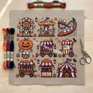 Könnte beinhalten: Ein Kreuzstichmuster auf beigem Stoff mit einem Halloween-Jahrmarkt-Thema, das ein Riesenrad, ein Karussell, eine Achterbahn und verschiedene Marktstände zeigt. Das Design enthält Geister, Kürbisse, Eulen und schwarze Katzen in orangefarbenem, violettem und schwarzem Garn.