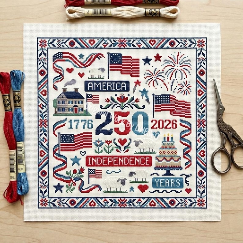 May include: A cross-stitch design featuring patriotic symbols in red, white, and blue. The design includes American flags, fireworks, a house, sheep, and the text "America," "Independence," "1776," "250," "2026," and "Years."