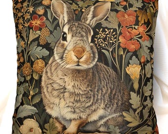 May include: A square throw pillow featuring a detailed illustration of a brown rabbit centered against a dark background filled with orange, yellow, and green botanical elements including various flowers, leaves, and stems in a dense pattern.