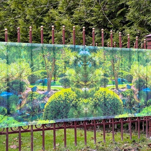 May include: A green and brown printed banner depicting a Japanese garden with a pond and trees. The banner is attached to a brown metal fence with decorative gold finials.