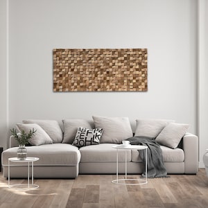 Könnte beinhalten: Ein hellgraues Ecksofa mit einer grauen Wolldecke und einem weißen Couchtisch in einem modernen Wohnzimmer mit einem Wandkunstwerk aus Holz über dem Sofa.