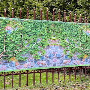 May include: A green ivy and stone wall printed on a banner, attached to a brown metal fence.