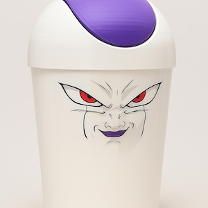 Puede incluir: Papelera blanca con tapa morada y un gráfico de Freezer de Dragon Ball Z. La cara del personaje se muestra prominentemente en la parte delantera, con ojos rojos y boca morada. La papelera tiene forma cilíndrica.