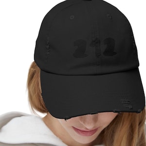 Peut inclure: Une casquette de baseball noire usée avec le numéro "212" imprimé en blanc sur le devant.