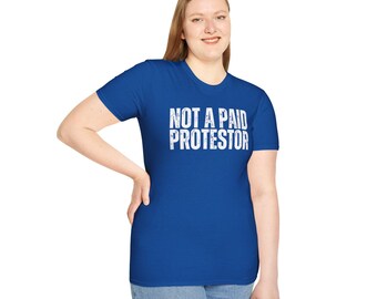 May include: A royal blue t-shirt with the white text "NOT A PAID PROTESTOR". The shirt is short-sleeved and has a crew neck. The model is wearing light blue jeans.