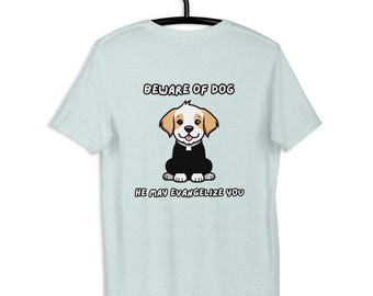 May include: Light blue t-shirt with a cartoon dog illustration. The dog is wearing a black robe and has tan ears. The text "BEWARE OF DOG" and "HE MAY EVANGELIZE YOU" are above and below the dog graphic.