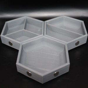 May include: Three gray hexagonal trays with magnetic closures. Each tray has a different number of compartments. The trays can be used to organize small items.