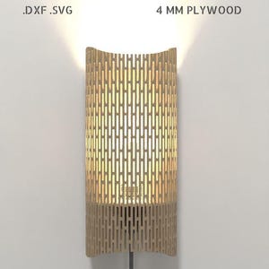 Può includere: Applique da parete in legno dal design cilindrico, con motivi verticali intagliati. Realizzata in compensato da 4 mm, emette una luce calda. Il testo "DOWNLOAD DIGITALE .DXF .SVG" è in alto.