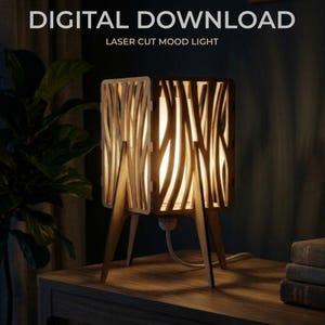 May include: A wooden laser-cut mood light with a warm glow. The lamp has a rectangular shape with vertical, curved cutouts. The lamp sits on three wooden legs and is plugged into an electrical outlet. The text "DIGITAL DOWNLOAD" and "LASER CUT MOOD LIGHT" are at the top.