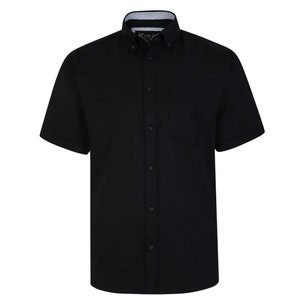 Puede incluir: Una camisa negra de manga corta con botones y cuello estampado en blanco y negro.