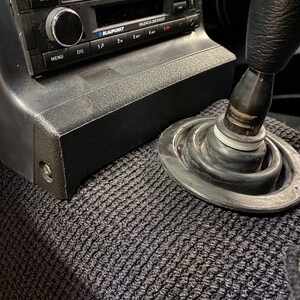 Könnte beinhalten: Ein schwarzes Autoradio mit einem silbernen Knopf und dem Text "BLAUPUNKT VALENCIA 200 DAB+ BT" auf der Vorderseite. Das Radio ist in einem schwarzen Armaturenbrett montiert. Ein schwarzer Schalthebel befindet sich im Vordergrund.
