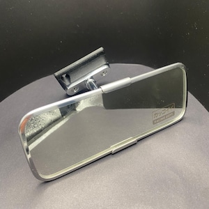 Può includere: Specchietto retrovisore cromato rettangolare con staffa di montaggio nera. Lo specchio ha una superficie riflettente e una cornice cromata. Il testo "RACING DEPT" è visibile sullo specchio.