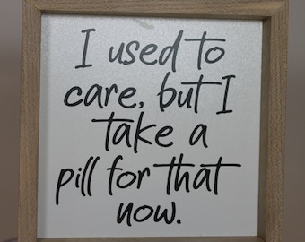May include: A wooden framed sign with a white background and black text that reads "I used to care, but I take a pill for that now."