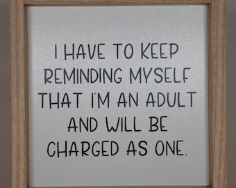 May include: A framed sign with a white background and black text that reads "I have to keep reminding myself that I'm an adult and will be charged as one."