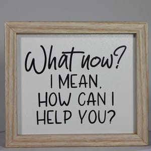 May include: A white framed sign with black text that reads "What now? I mean, how can I help you?"