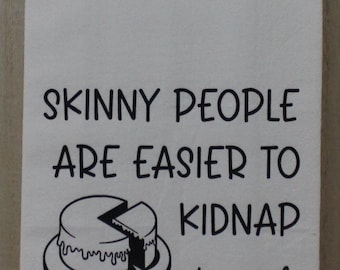 May include: White kitchen towel with black text that reads "SKINNY PEOPLE ARE EASIER TO KIDNAP stay safe eat cake." A black and white cake illustration is also featured.