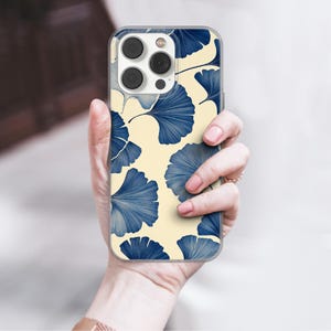 May include: A clear phone case with a cream background and a blue and white ginkgo leaf pattern.