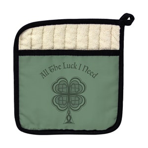 Puede incluir: Manopla de cocina verde con borde negro y parte posterior acolchada blanca. Presenta un trébol de cuatro hojas con un diseño de nudo celta y el texto "All the Luck I Need".