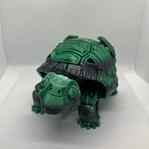 May include: A 3D printed green and black turtle figurine with a detailed shell and mechanical legs.