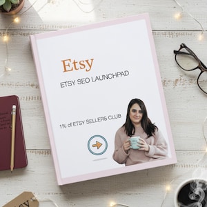 May include: A pink-framed book titled "Etsy SEO Launchpad" with the Etsy logo in orange. The book features an image of a woman holding a mug. A tag with the Etsy logo and a cup of coffee are also visible.