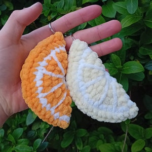 May include: Two crocheted citrus fruit keychains, one orange and one white, with a silver key ring.