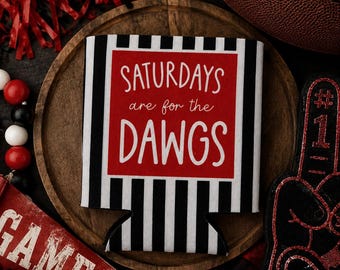 May include: A black and white striped beverage insulator featuring a red rectangular center panel with the white text "SATURDAYS are for the DAWGS" printed in a mix of script and block lettering, centered on a circular wooden base.
