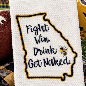 May include: A white waffle-weave kitchen towel featuring an embroidered outline of the state of Georgia in navy and gold thread. The text "Fight. Win. Drink. Get Naked." is embroidered in navy blue, accompanied by a small yellow and black bee icon.