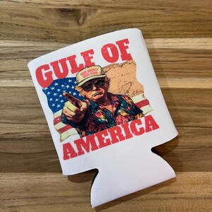 以下が含まれることがあります： 「GULF OF AMERICA」の赤い文字が入った白い缶クーラー。デザインは、アメリカの国旗と地図とともに、指をさしている男性が特徴です。「MAKE AMERICA GREAT AGAIN」と書かれた帽子をかぶっています。