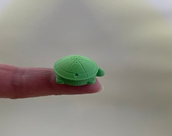 May include: A small green turtle eraser with a detailed shell design.