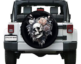 May include: A black spare tire cover with a white skull and pink and black roses. The tire cover is on a white Jeep Wrangler.