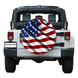 May include: A white Jeep with a spare tire cover featuring an American flag design. The tire cover is red, white, and blue with a wavy, flowing design. The Jeep has a black roll bar and a sticker that reads "Style My Whip Tire Covers & More".