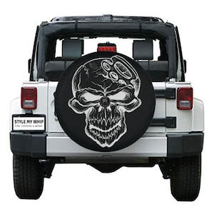 May include: A white Jeep with a black skull and crossbones spare tire cover. The cover has the text "STYLE MY WHIP TIRE COVERS & MORE" on the bottom left corner.