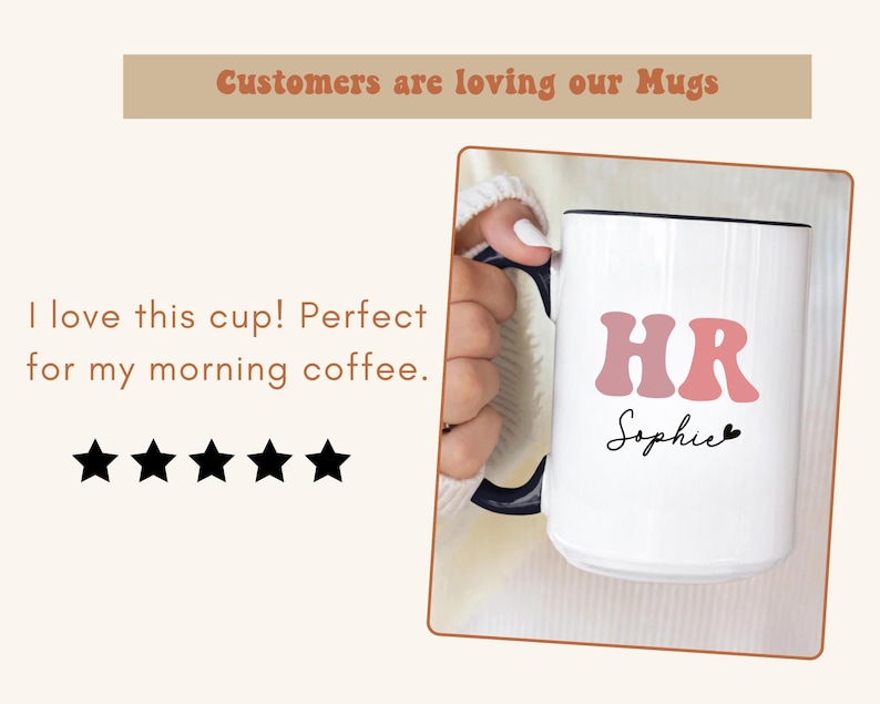 May include: White ceramic mug with a black rim and handle. The mug has pink letters that spell "HR" and the name "Sophie" written in black cursive. The mug is being held by a hand.