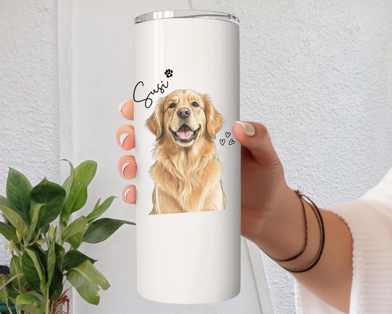 May include: A white stainless steel tumbler featuring a golden retriever illustration. The dog's name, "Susi", is written in cursive above the image, along with a paw print and three small hearts.